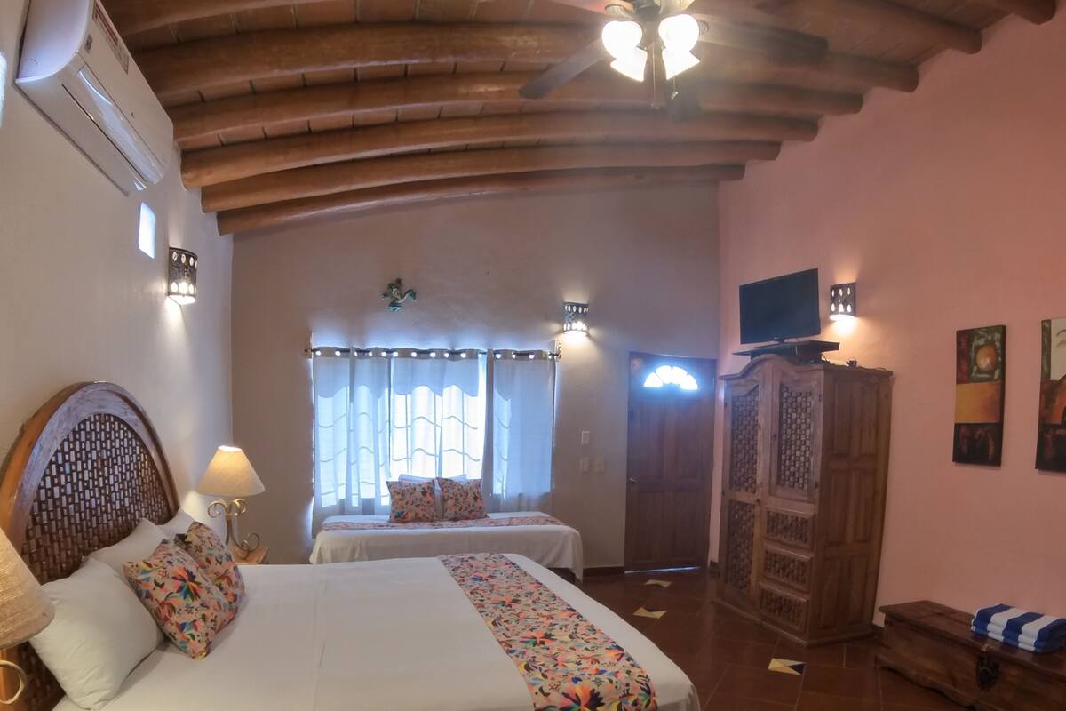 A room with two beds, a ceiling fan, a TV, and a wardrobe.