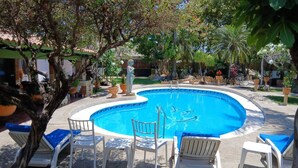 A swimming pool with lounge chairs and a statue in the center. - Casa Virgilio B&B (Nuevo Nayarit)
