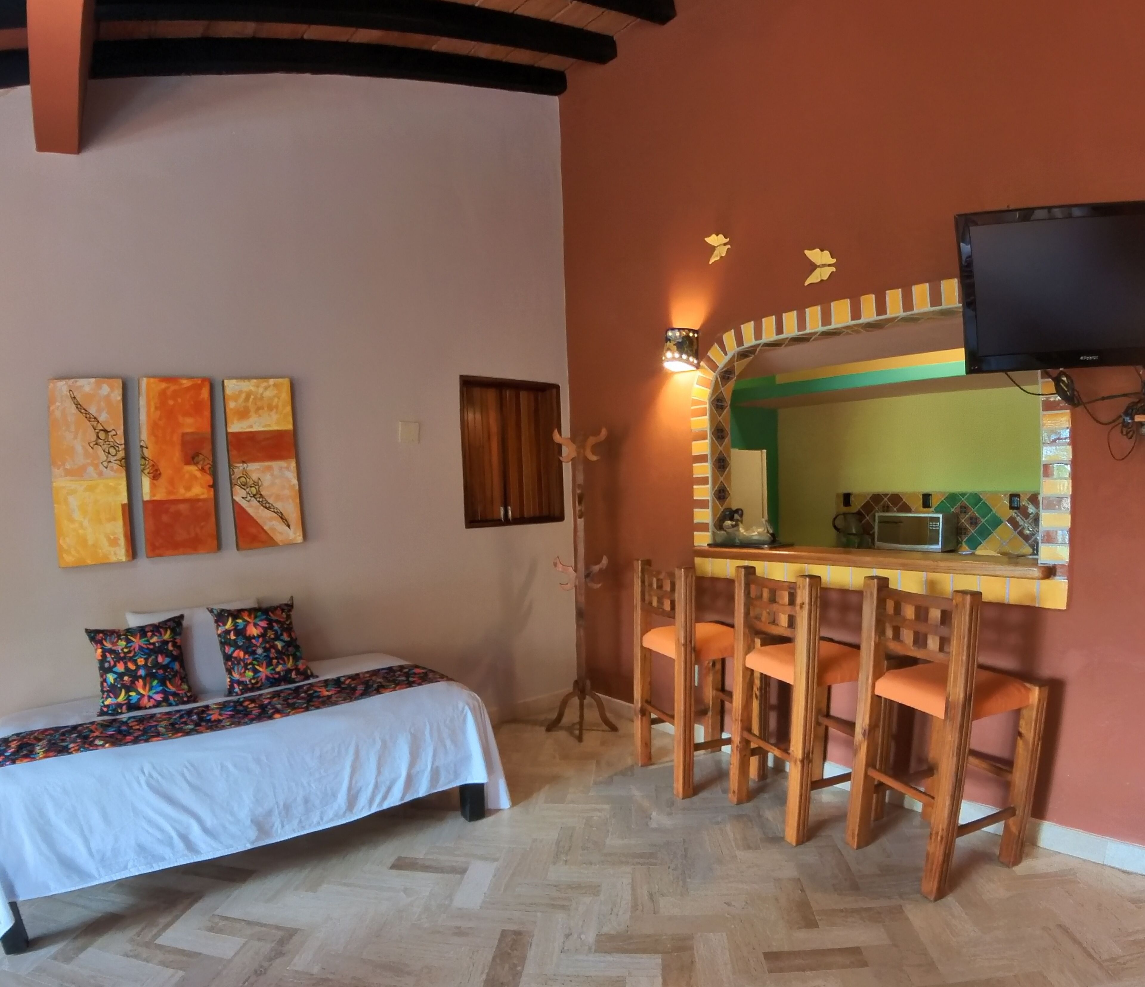 Ein Zimmer mit einem Bett, einem Essbereich mit Stühlen, einem Fernseher und Bildern an der Wand.