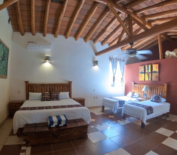 A bedroom with two beds, a wooden ceiling, a tiled floor, and a nightstand with a lamp. - Casa Virgilio B&B (Nuevo Nayarit)