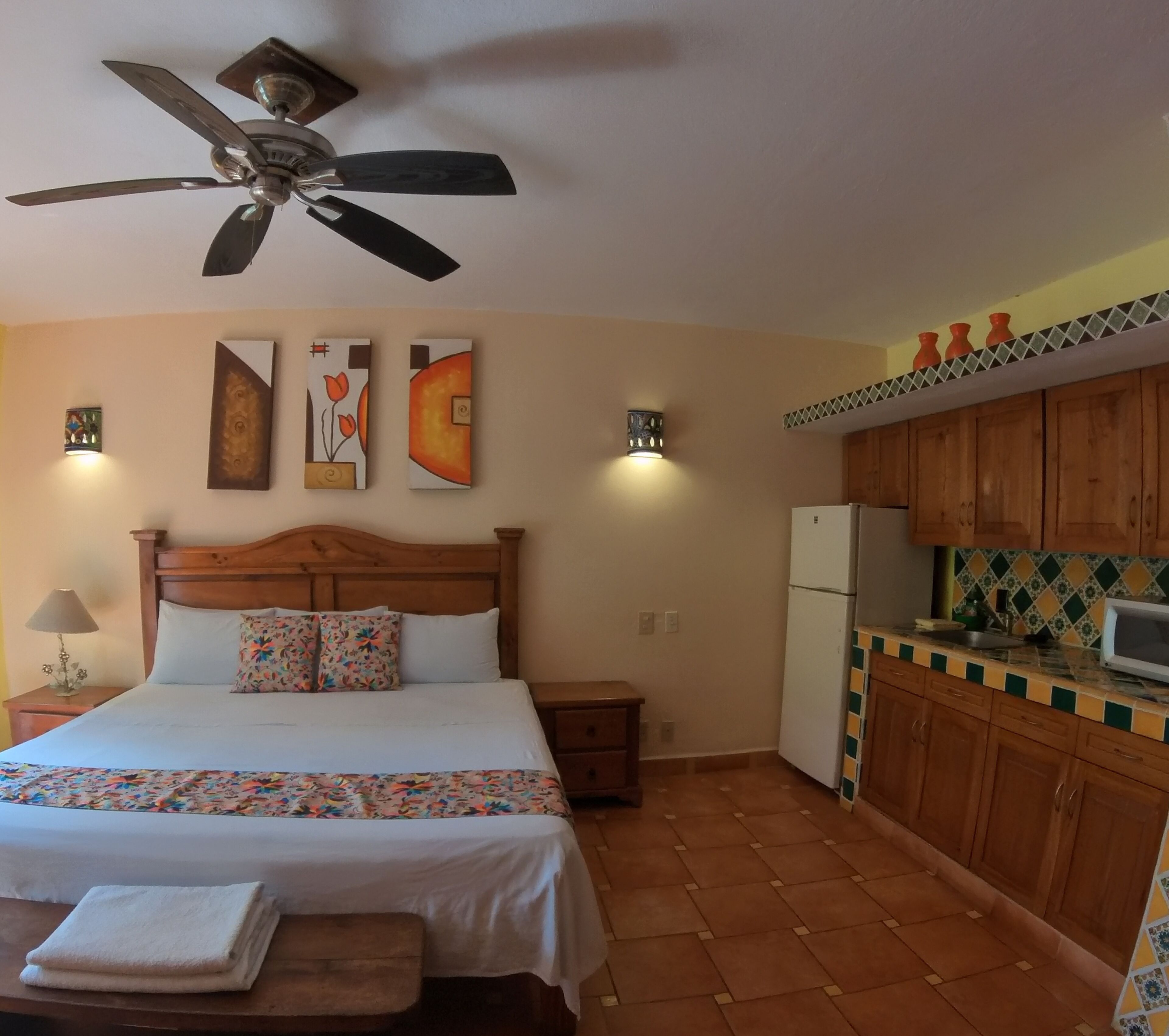 A bedroom with a bed, a ceiling fan, a nightstand, a bedside lamp, and a small table with a folded towel.