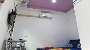 A small, compact room with a bed, a desk, and a ceiling fan. - Sroe Ground Homestay (Sanom)