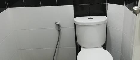A bathroom with a toilet, a shower, and a sink.