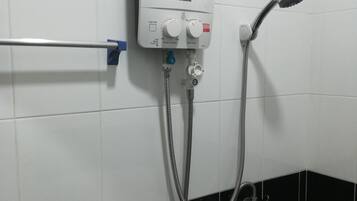 Un baño con pared de azulejos blancos y negros, una ducha eléctrica Panasonic y un perchero.