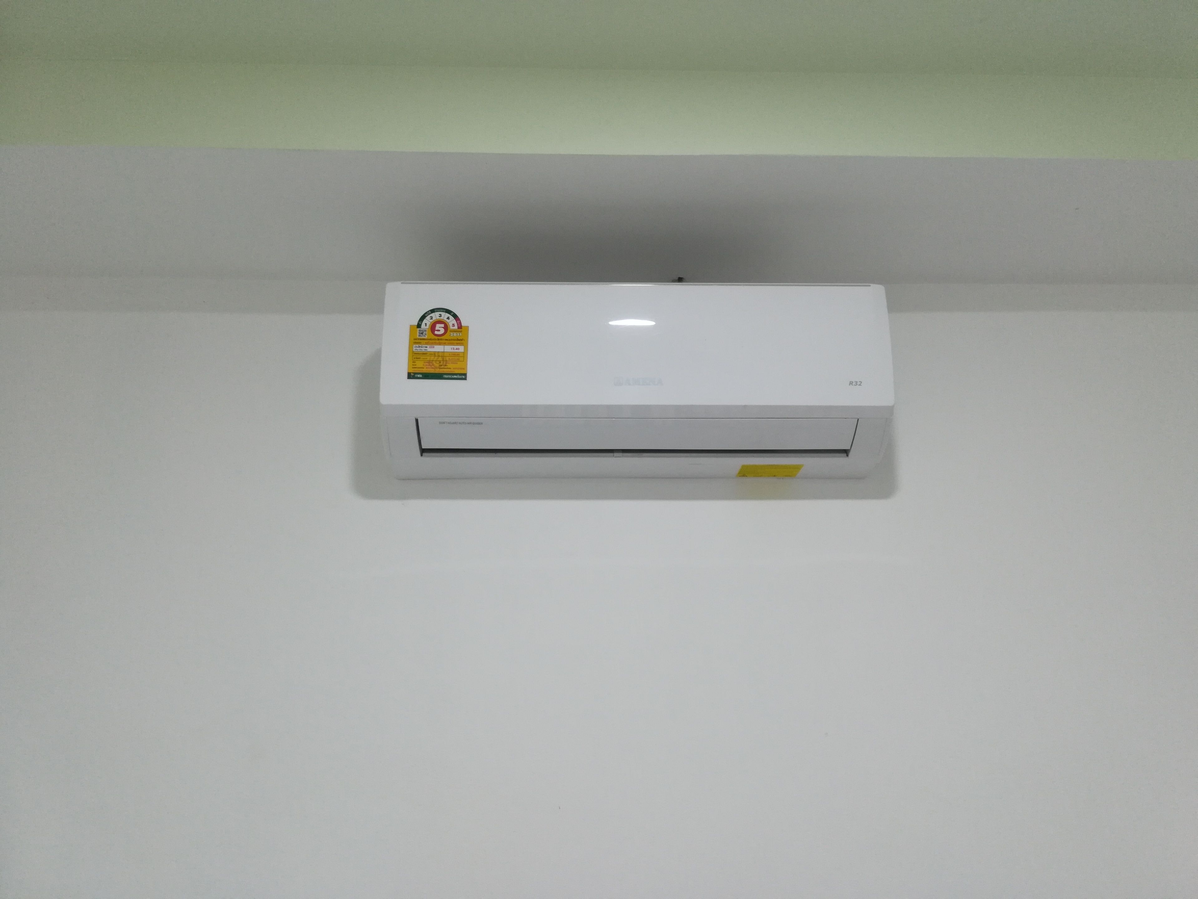 A white wall-mounted air conditioner with a visible sticker and a label on the front.