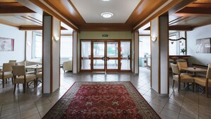A spacious lobby with a red carpet, wooden ceiling, and a glass door entrance. - Hotel Mörbischerhof (Morbisch am See)
