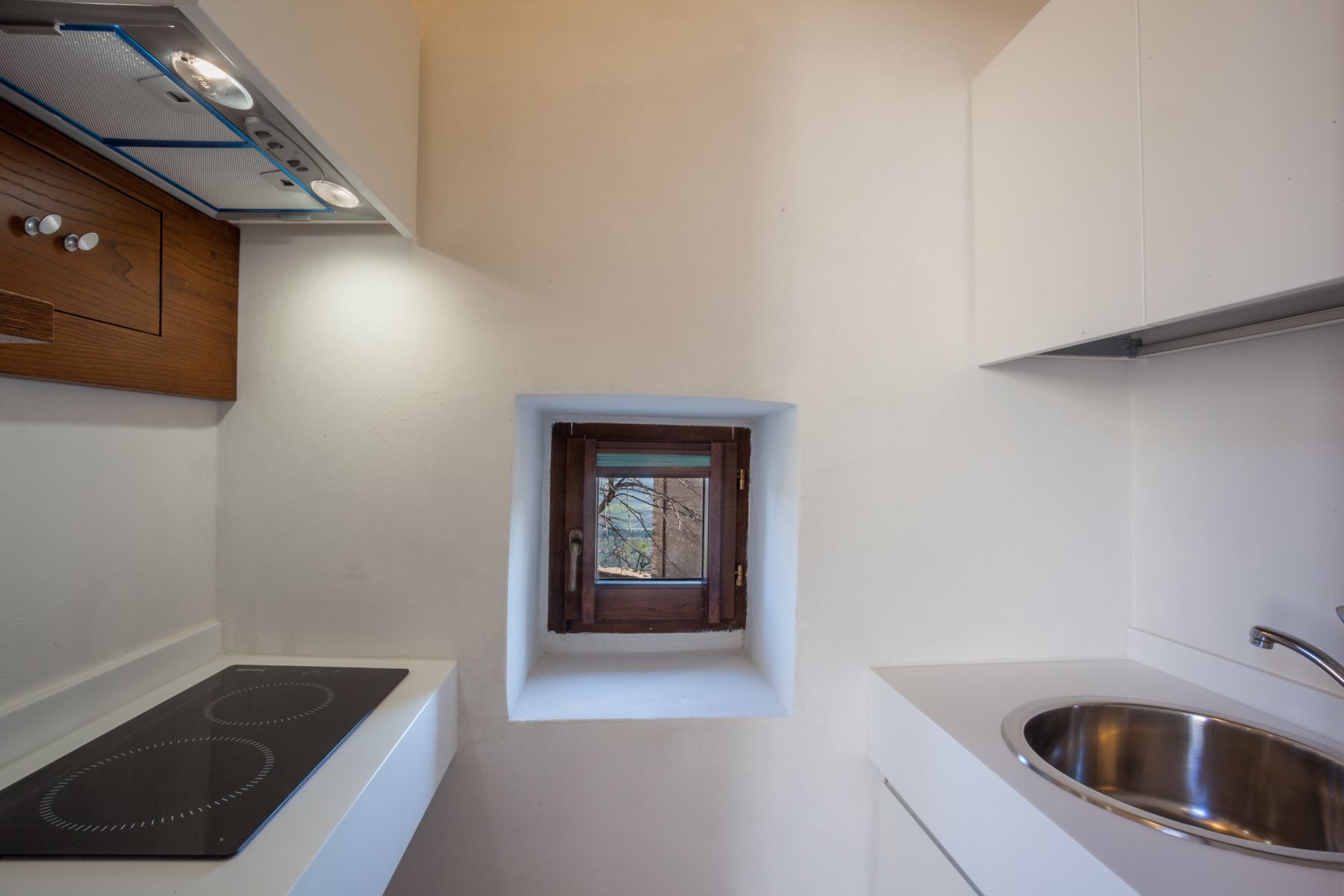 A compact kitchen with a built-in stove, a small window, and a stainless steel sink.