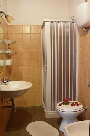 A bathroom with a shower enclosure, toilet, sink, and a towel rack. - Hotel Orizzonte Blu di Tropea (Ricadi)