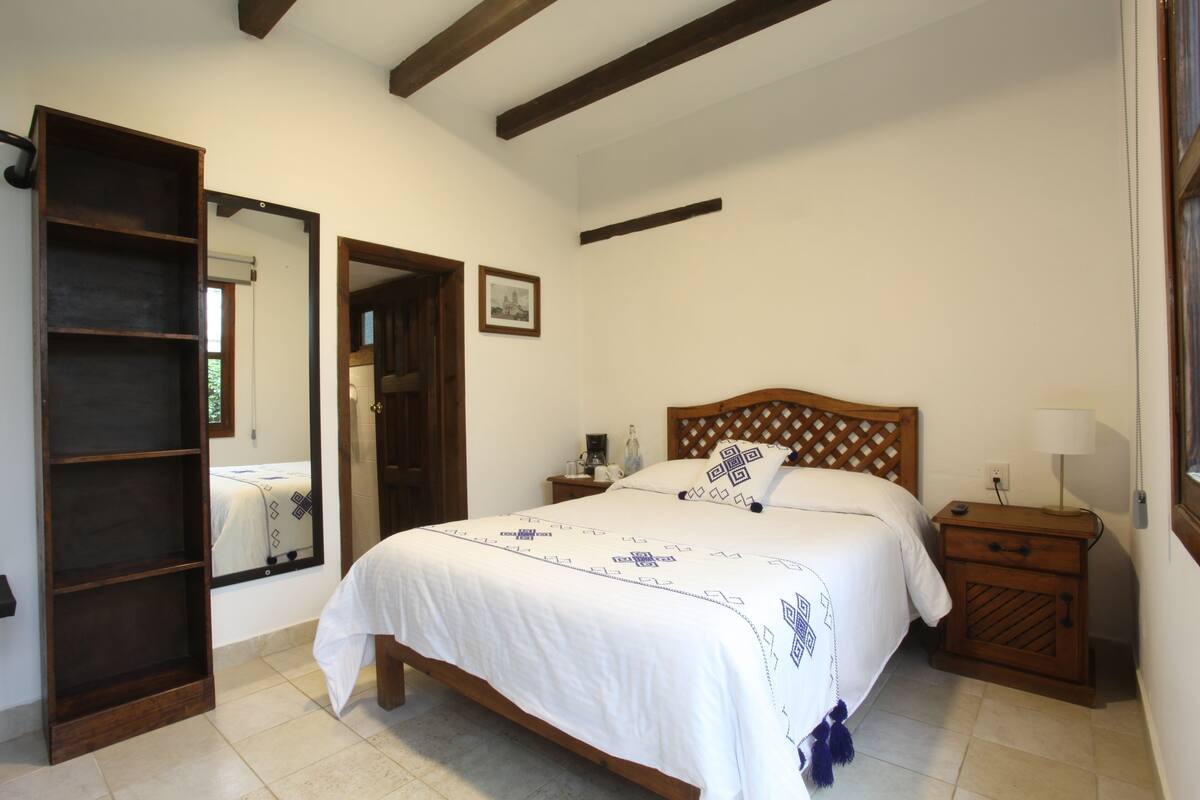 Un dormitorio con una cama de madera, una mesita de noche, un tocador, un espejo y un armario.