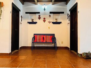 A hallway with a bench, two doors, and wall decorations. - Hotel Ocho Barrios (San Cristóbal de las Casas)