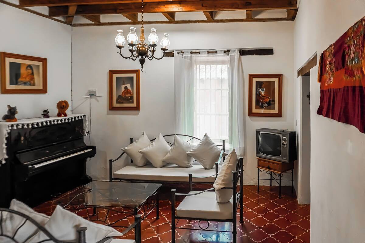Una habitación con cama, piano, televisión y candelabro.