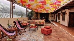 A cozy patio area with a hammock chair, cushioned seating, and potted plants.