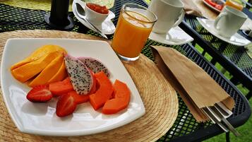 A breakfast setting with a plate of sliced fruits and a glass of orange juice on a table.