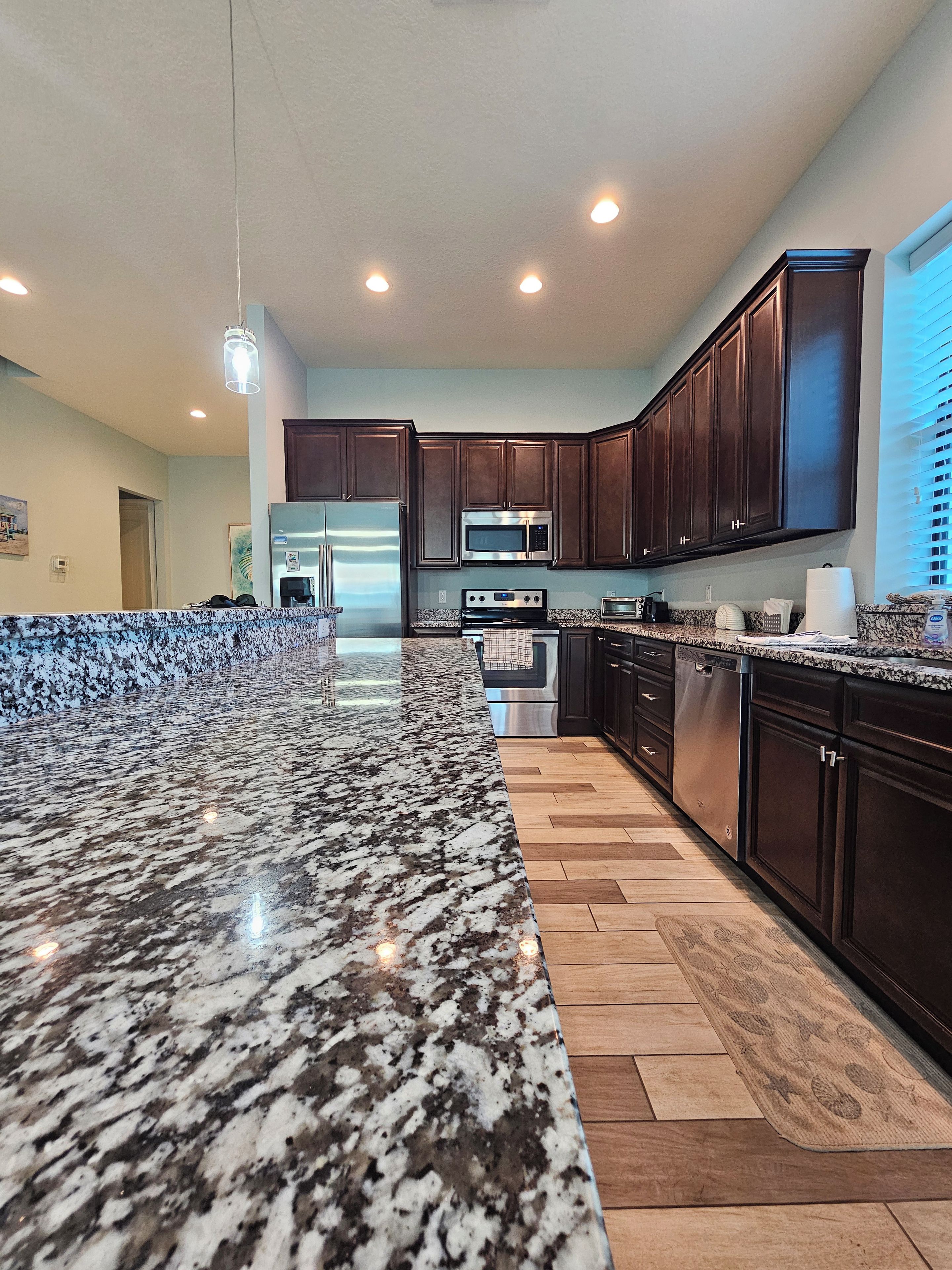 A modern kitchen with granite countertops, stainless steel appliances, and dark wooden cabinets.