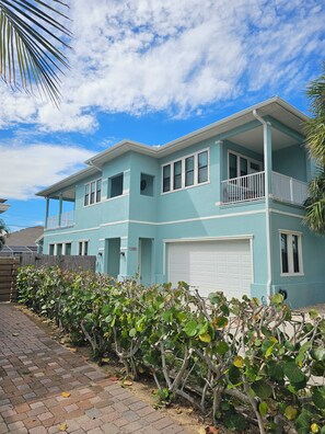 A two-story house with a balcony, a garage, and a brick pathway.