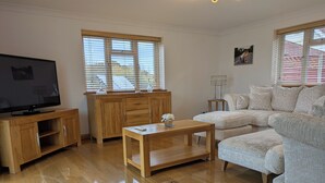 Un salon avec un meuble TV en bois, une table basse en bois, un canapé beige et un buffet en bois.