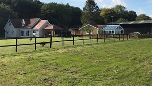 Une propriété rurale comprenant une grande maison, une serre et un champ clôturé.