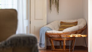 Una habitación con una silla de mimbre, una mesa de madera y una puerta.