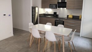 A modern kitchen with a white table and four chairs, stainless steel appliances, and wooden cabinets.