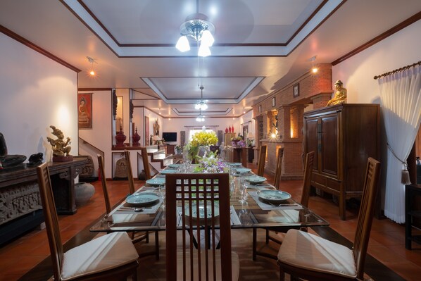 A dining area with a long table set for a meal, surrounded by chairs.