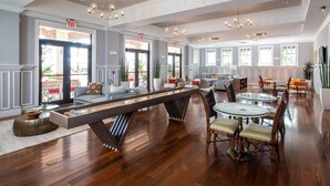 A spacious hotel lobby with a long reception desk, multiple seating areas, and large windows allowing natural light.