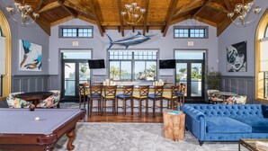 Une pièce spacieuse équipée d’une table de billard, d’un canapé bleu et d’un coin repas avec des chaises et une table.