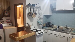 Una cocina compacta con electrodomésticos blancos, una mesa de madera y un respuesto de azulejos azules.