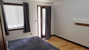 Un dormitorio con cama, puerta y ventana con cortinas.
