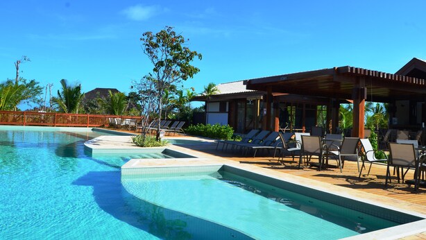 Zona de piscina con sillones de descanso y un área de estar cubierta.