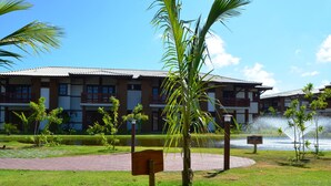 Un hotel con patio, palmeras, fuente de agua y sendero de ladrillo.