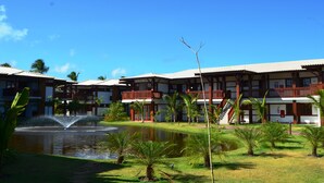 Un hotel con varios balcones, una fuente central y palmeras.