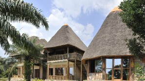 Ein Resort mit strohgedeckten Gebäuden, einem Pool und üppiger Vegetation.