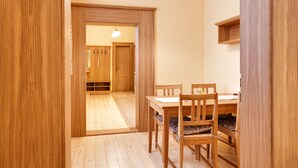 Un coin repas en bois avec une table et des chaises, une armoire en bois et un couloir menant à une autre pièce.
