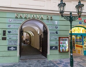 L'ingresso di Karlova 25 con indicazioni per un caffè, una galleria d'arte, un negozio di tatuaggi e piercing e un pub.