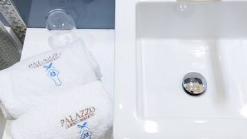 A white bathroom sink with a drain stopper and a glass of water on the counter.
