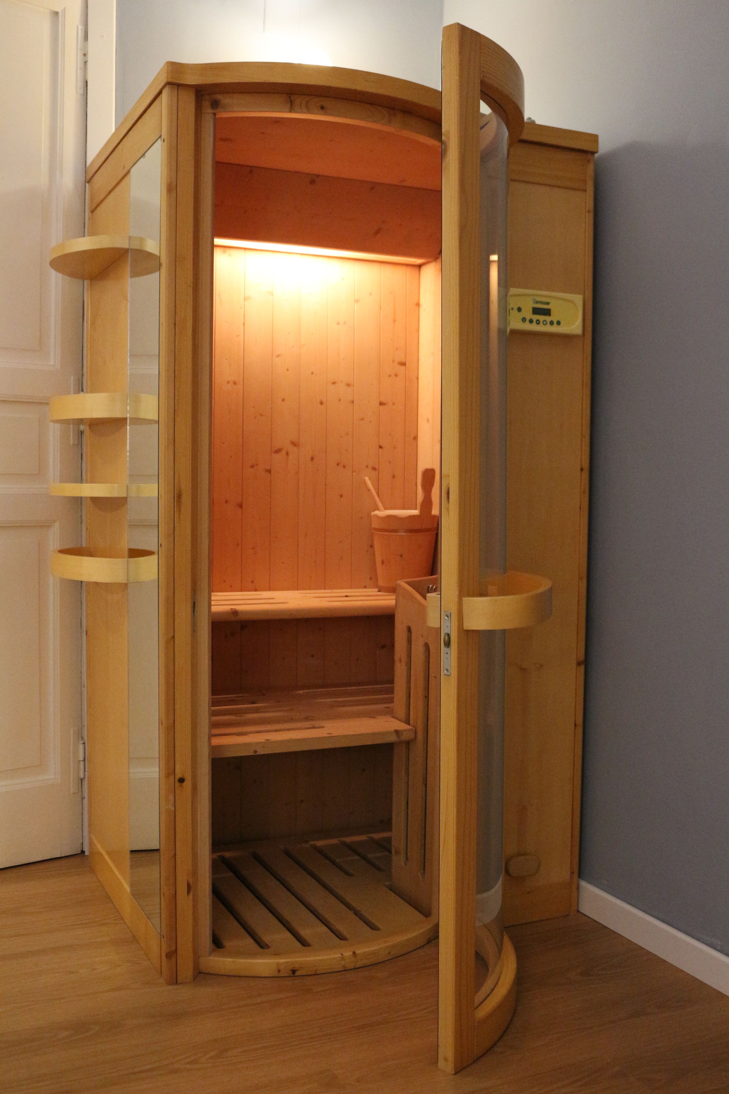 A wooden sauna with a bench, a small table, and a heater.