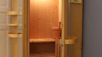 A wooden sauna with a bench, a small table, and a heater.