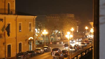 Ein belebtes Stadtbild bei Nacht mit Gebäuden und parkenden Autos.