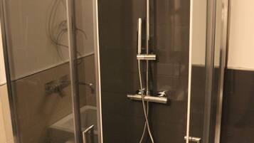 A modern bathroom with a glass-enclosed shower, a white sink, and a towel rack.