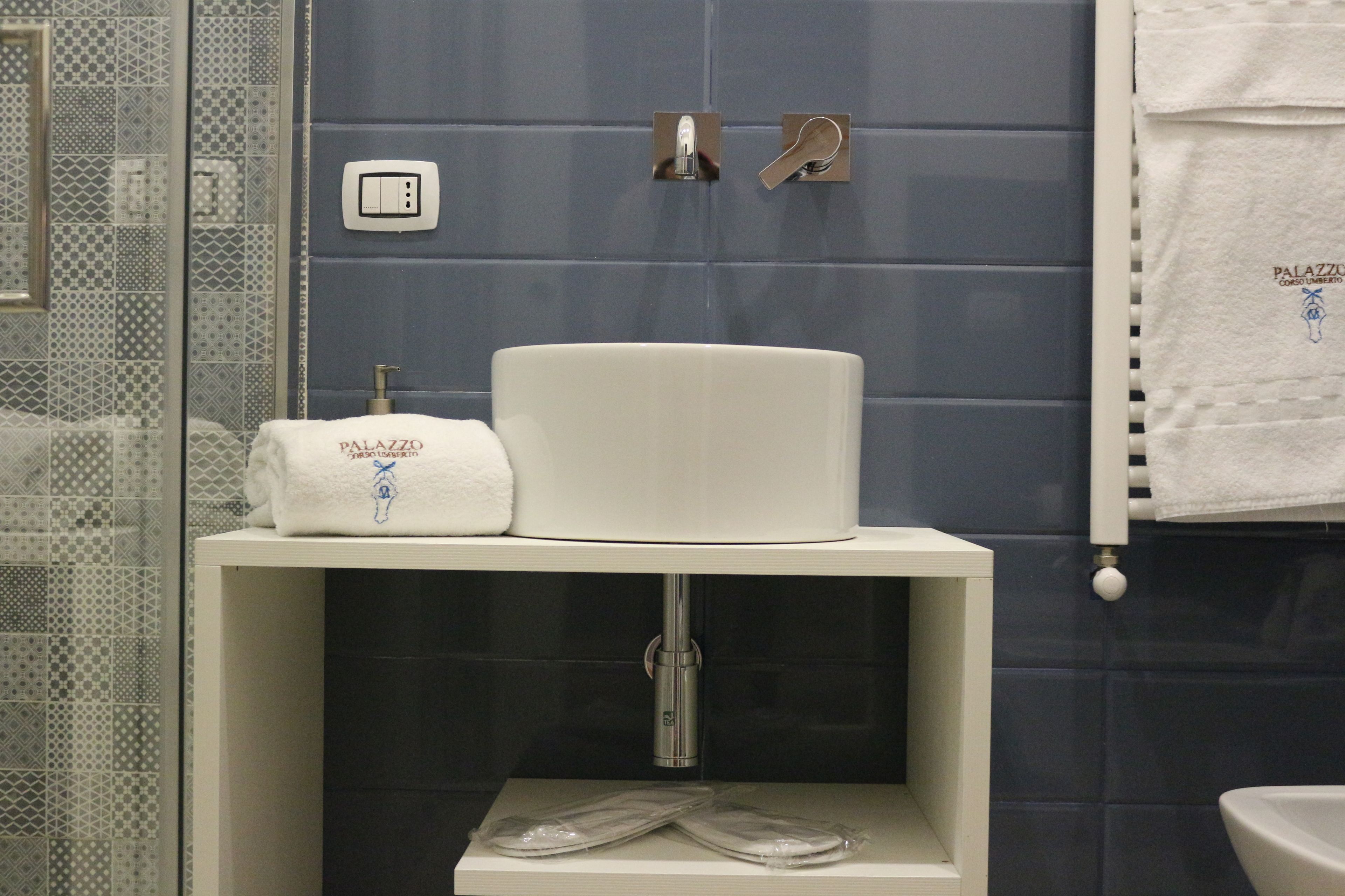 Un baño con lavamanos blanco, una toalla y zona de ducha.