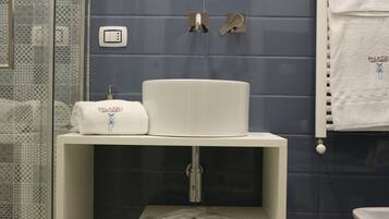 Un baño con lavamanos blanco, una toalla y zona de ducha.