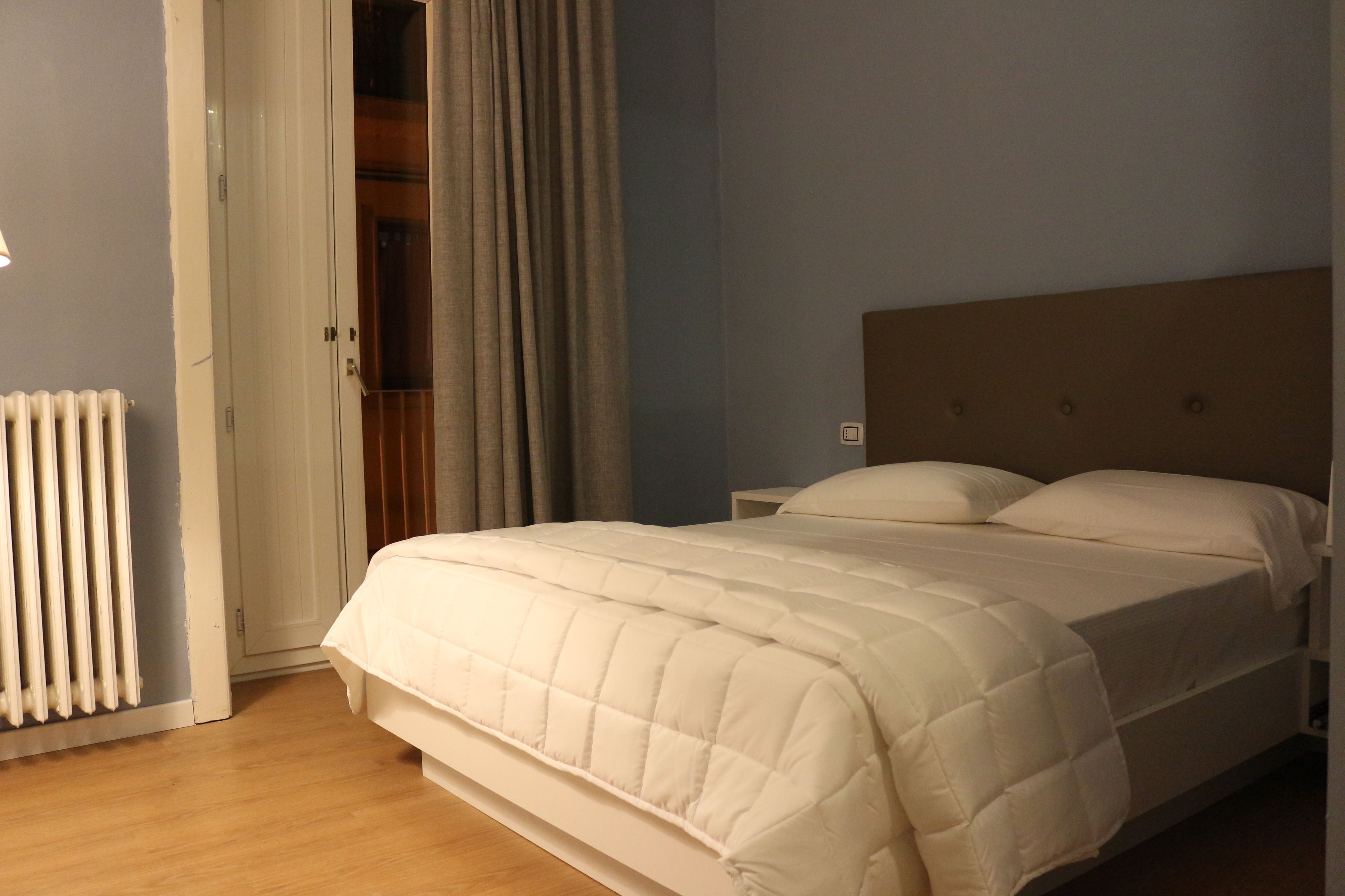 Una camera da letto con un letto, un comodino e un termosifone.