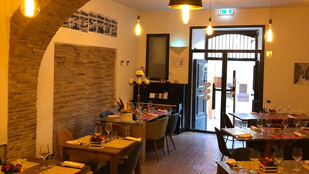 Een restaurant met bakstenen bogen, houten tafels en hangende lampen.