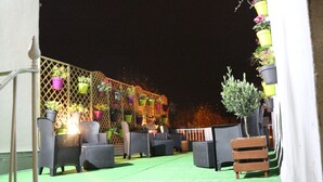 Een terras buiten met rieten meubels en plantenpotten.