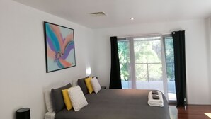 Ein modernes Schlafzimmer mit einem großen Bett, einem Bild an der Wand und Blick durch das Fenster.