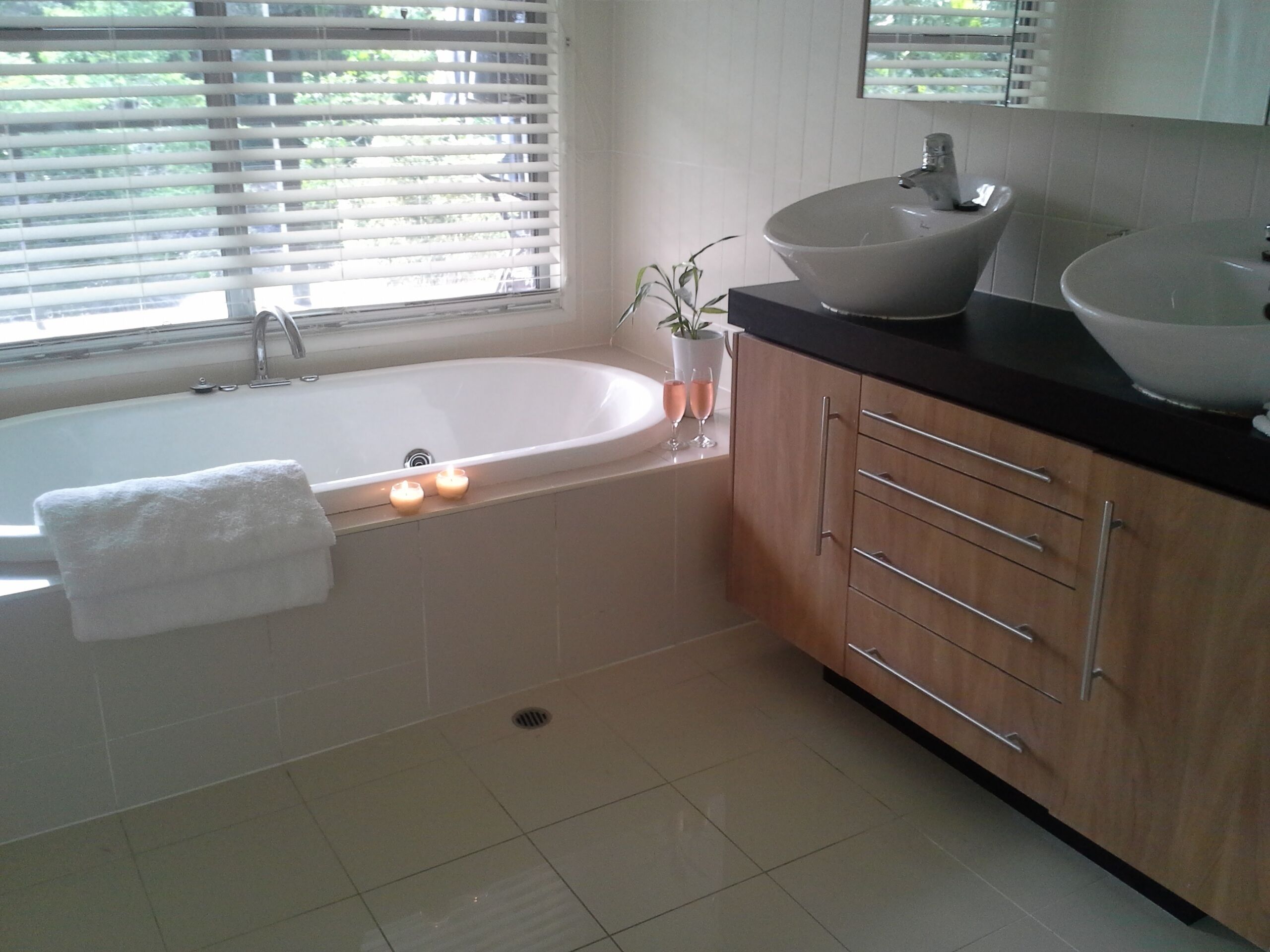 A modern bathroom with a bathtub, two sinks, and wooden cabinets.