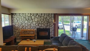 A living room with a stone wall, a fireplace, a sofa, a coffee table, and a television.
