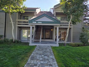A two-story building with a front entrance, a staircase, and a paved driveway.