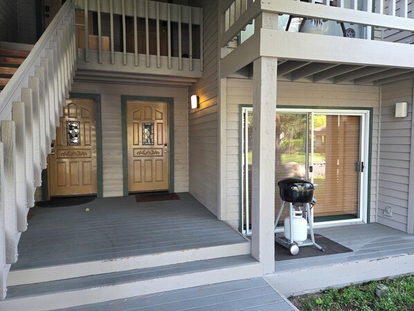 A two-story house with a front porch, a wooden staircase, and a sliding glass door.