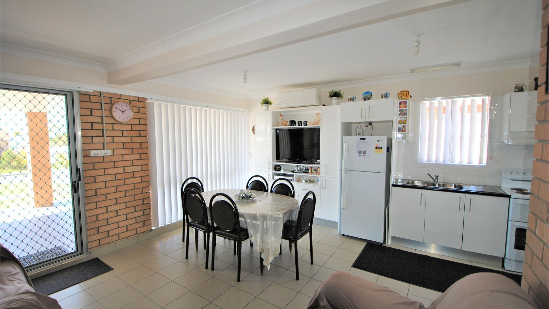 A compact living space with a dining area, kitchenette, and a sliding glass door leading to an outdoor area.